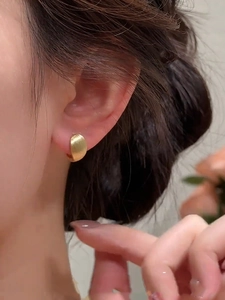 Detailed view of 18k gold plated brushed oval earrings worn on model for a luxury look