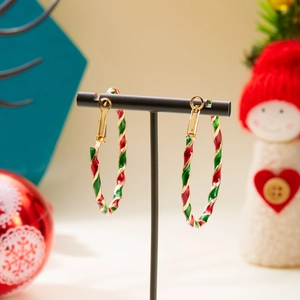 Detail of Christmas candy cane style twisted gold hoop earrings with red and green enamel