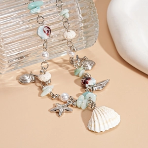 Close-up of ocean-style necklace with shell charms and colorful beads on a glass bottle