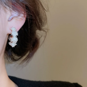 Close-up of sparkling floral silver stud earrings on model with high quality metal texture