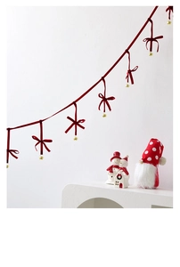 Detail of red velvet Christmas garland with golden bells and handmade bows for holiday decor