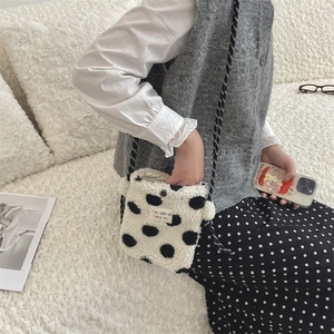 Detail of plush polka dot shoulder bag showing soft texture and woven label brand tag