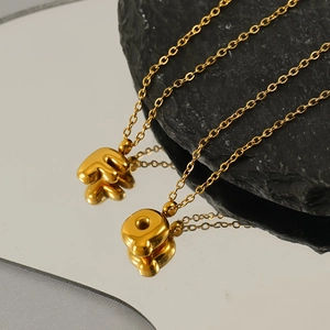 Macro shot of 3D bubble style letter F and Q pendants in polished gold finish