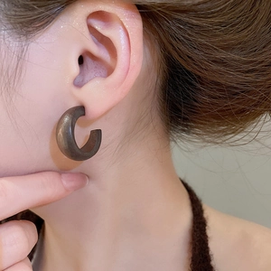 Gros plan d'une boucle d'oreille ronde en bois évidé avec motif floral et texture naturelle