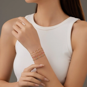 Elegant gold link bracelet with white, pink, rose, and blue pearls on a woman's wrist