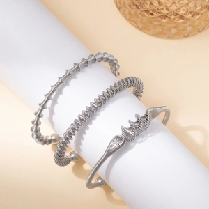 Three-piece set of silver spiral stainless steel bracelets on a white display stand