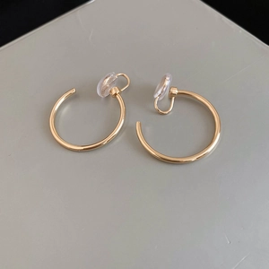 Detail view of gold round clip-on earrings with clear silicone comfort pads