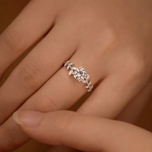 Close-up of laurel leaf silver ring with moissanite flower design on finger