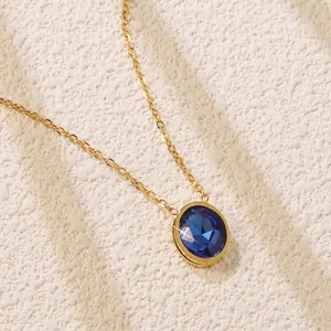 Detail of gold necklace with large multifaceted oval blue gemstone pendant on white background