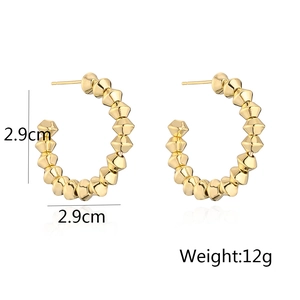 Detail view of gold-plated C-shaped stud earrings featuring spiked rivet design details