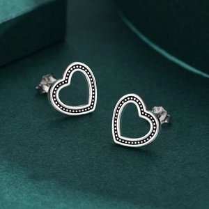Minimalist S925 sterling silver hollow heart stud earrings on dark green velvet