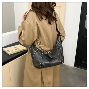 Detail of black vintage hobo bag featuring golden rivets and leather tassels on model