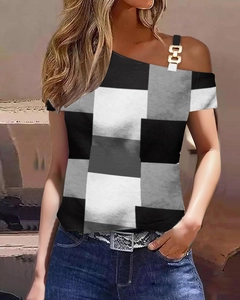 Detail eines One-Shoulder-Tops mit schwarz-weißem Gittermuster und goldener Ketten-Schnalle