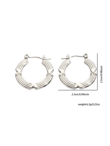 Dettaglio di orecchini a cerchio argento con texture geometrica e dimensioni di 2,5 cm