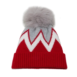 Dettaglio del cappello invernale in maglia con strisce rosse a zigzag e pompon grigio