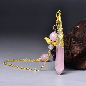 Detail of rose quartz hexagonal prism pendant with gold floral cap and wing charm