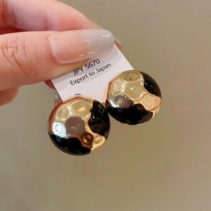 Detail shot of vintage round earrings with gold hammered metal and black enamel texture