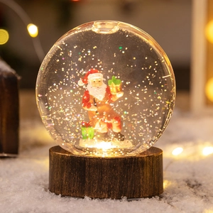 Boule de cristal de Noël lumineuse avec figurine de Père Noël et neige scintillante