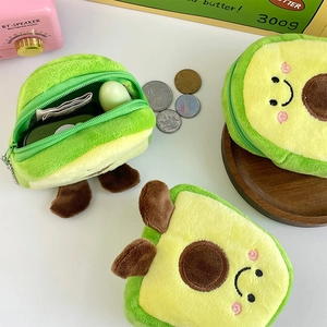 Macro shot of avocado plush coin purse holding coins and lipstick on a white desk