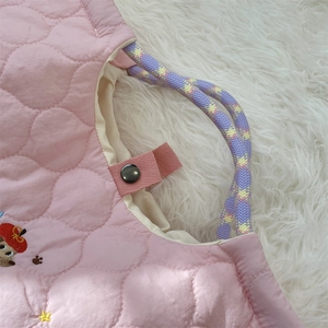 Detail of pink quilted tote bag with purple woven rope handle and secure metal snap button