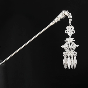 Detailed view of silver Hmong hair pin featuring intricate filigree and swaying tassels