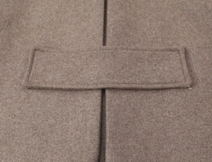 Detail of the sleeve strap and fine stitching on a brown wool blend short coat