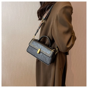 Detail of vintage black textured leather handbag with gold twist lock and ethnic strap