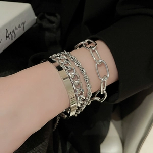Close-up of four-piece silver metal chain and cuff bracelet set on a model's wrist