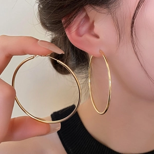 Detailed view of large polished gold hoop earrings on model for a minimalist style