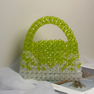 Detail of lime green and clear acrylic handmade beaded handbag on textured fabric