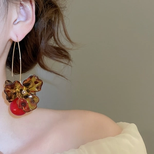 Detailed view of vintage amber resin flower earrings with red bead cherry charm