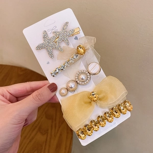 Detail of 5-piece hair clip set featuring rhinestone starfish, mesh bow and pearl accents