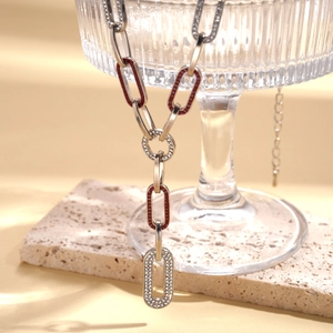 Oval link chain necklace with red enamel and sparkling crystal pavé on warm background