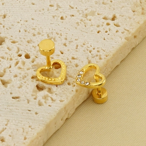 Elegant gold heart stud earrings with sparkling crystals on a textured stone display