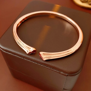 Detailed close-up of rose gold open bracelet with ridged fold texture on a leather box