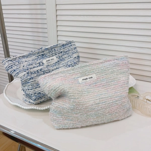 Close-up of blue and pink tweed makeup bags with simple wish labels on white tray