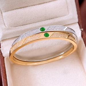 Detail of 18K gold and silver plated bangles with green gemstones and pavé stones