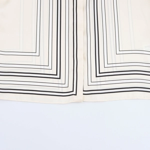Macro detail of beige satin shirt fabric featuring elegant black and gray geometric stripes