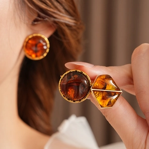 Detail view of amber resin geometric earrings with gold metal frame on a model