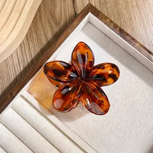 Elegant amber tortoiseshell flower hair claw clip displayed in a wooden jewelry box