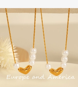 Détail d'un collier pendentif cœur doré avec trois perles blanches sur chaîne serpent