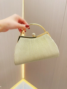 Detail of champagne gold evening clutch with pleated texture and rhinestone clasp