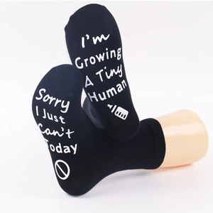 Detail view of anti-slip soles with I'm Growing A Tiny Human text on black cotton socks