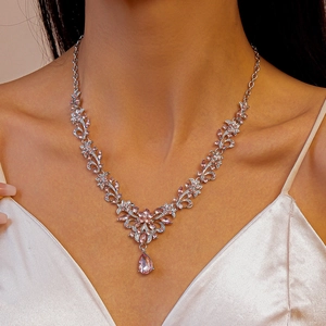 Detail of silver necklace with pink rhinestone flower and teardrop pendant on model