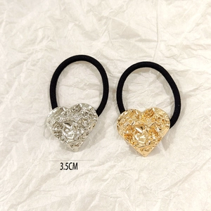 Detailed view of 3.5cm gold and silver heart-shaped hair ties with hammer texture on paper