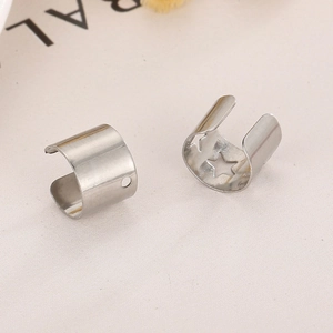 Polished stainless steel ear cuffs featuring star and circle cutouts on beige fabric