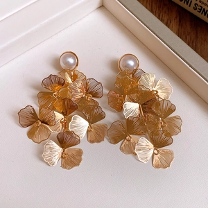 Détail macro de boucles d'oreilles fleuries or champagne avec pétales texturés et perles
