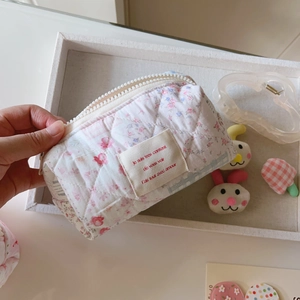 Détail macro de la trousse matelassée fleurie avec fermeture et étiquette en tissu
