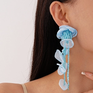 Detail of light blue handmade lace flower earrings with beaded tassels on model