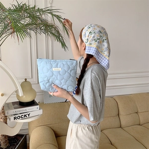 Detailed view of light blue quilted floral makeup bag with a soft fabric texture